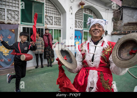 (181029) - Yan'an, Oktober 29, 2018 (Xinhua) - Zhou Zhifu (R) hit Becken zu helfen, seinen Enkel lernen Taille drum Tanz in Ansai Fengjiaying Dorf im Bezirk, Yan'an, Provinz Shaanxi im Nordwesten Chinas, Okt. 19, 2018. Ansai Bezirk, im nördlichen Teil der Provinz Shaanxi auf dem Löß-Plateau, ist bekannt für seine einzigartige Volkskunst wie Ansai Taille Drum Dance bekannt, Papier-cut, Volkslieder, volkstümliche Malerei und Oper. In den letzten Jahren, Ansai hat sich bemüht, den kulturellen Tourismus durch die Integration von Tourismus mit diesen einzigartigen Volkskunst, um der Armut zu fördern. Nach einer Schulung, Mitarbeiter Stockfoto