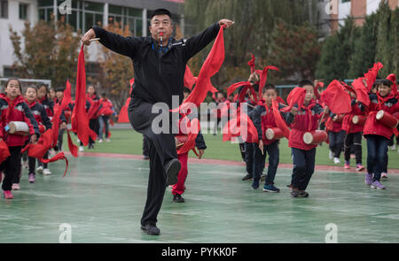 (181029) - Yan'an, Oktober 29, 2018 (Xinhua) - Sportlehrer Cheng Lang (vorne) führt eine Praxis der Ansai taille Tanz an der Nr. 2 der Grundschule in Ansai in Yan'an City, in der Provinz Shaanxi im Nordwesten Chinas, Okt. 22, 2018 drum. Ansai Bezirk, im nördlichen Teil der Provinz Shaanxi auf dem Löß-Plateau, ist bekannt für seine einzigartige Volkskunst wie Ansai Taille Drum Dance bekannt, Papier-cut, Volkslieder, volkstümliche Malerei und Oper. In den letzten Jahren, Ansai hat sich bemüht, den kulturellen Tourismus durch die Integration von Tourismus mit diesen einzigartigen Volkskunst, um der Armut zu fördern. Nach einigem Training". Stockfoto
