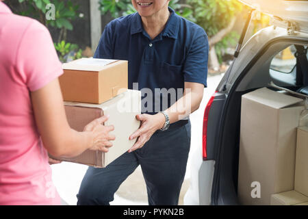 Frau empfangen Paket Karton ab Lieferung Mann, der Kurier Versand Mail, online eine Bestellung beim Stehen vor dem Haus Stockfoto