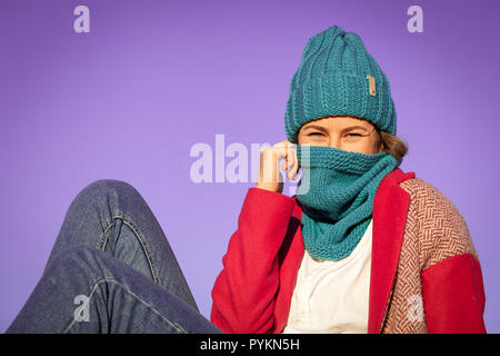 Porträt einer schönen jungen Modell in Strickmütze und warme Kleidung hält auf mysteriöse Weise ein Schal wie ein Schleier, den Tag genießen, um blauen Himmel im sonnigen Herbst Stockfoto