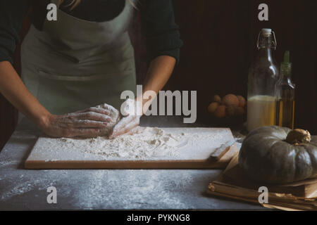 Hände kneten den Teig von Frauen. Backzutaten auf hölzernen Tisch Kürbis Milch Öl Mehl Stockfoto