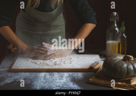 Hände kneten den Teig von Frauen. Backzutaten auf hölzernen Tisch Kürbis Milch Öl Mehl Stockfoto