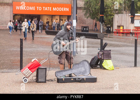 Ein strassenmusikant spielt eine Gitarre und Gesang außerhalb der Tate Modern auf der South Bank, London, England, Großbritannien Stockfoto