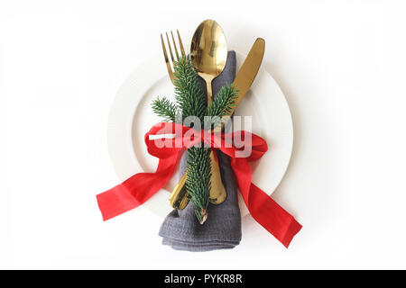 Traditionelle weihnachtliche Tisch setzen. Golden Besteck, Bettwäsche, Servietten, Grüne fichte Äste, Platte und red ribbon Dekoration auf weißem Hintergrund. Urlaub Hintergrund. Flach, Ansicht von oben Stockfoto