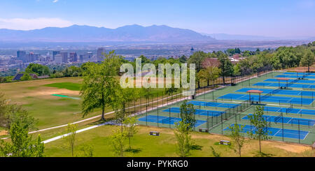 Sunlit Tennisplätze mit Stadt- und Bergblick Stockfoto