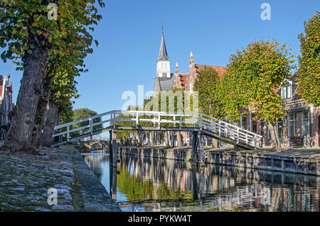 Sloten, Niederlande, 28. Oktober 2018: Blick entlang der Länge des Baumes - hauptkanal im Herbst ausgerichtet auf eine weiße Holzbrücke und den Turm von Stockfoto