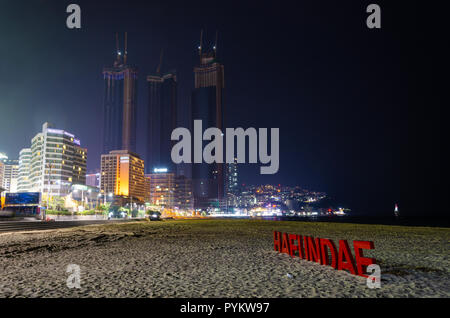 Haeundai Strand bei Nacht mit Wolkenkratzern der Stadt leuchtet im Dunkeln. Haeundae, Busan, Südkorea. Stockfoto