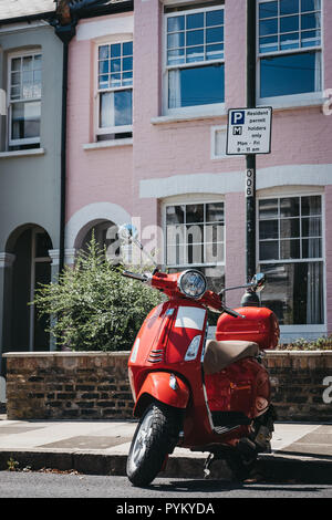 London, Großbritannien - 1 August 2018: Rote Vespa Motorrad durch ein Haus in Barnes, London geparkt. Vespa ist eine berühmte italienische Marke von Scooter hergestellt von Piagg Stockfoto