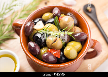 Marinierte Oliven mit Knoblauch, Rosmarin, Olivenöl und Gewürzen. Im rustikalen Stil Stockfoto