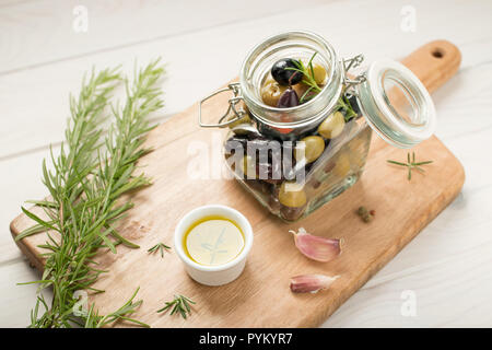 Vielzahl von Oliven in einem jar mariniert. Knoblauch, Rosmarin, Olivenöl und Gewürzen. Im rustikalen Stil Stockfoto