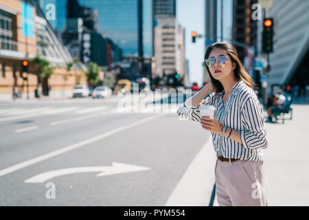 Weibliche Arbeitnehmer stehen im Zentrum der Stadt. junge Dame im Büro shirts warten Taxi neben der Strasse. geschäftsfrau Holding Kaffee nach Hause gehen Stockfoto