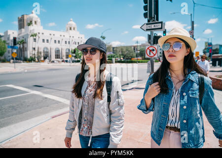 Weibliche Touristen zu Fuß auf der Straße mit Hut und Sonnenbrille an einem sonnigen Tag. junge Mädchen zu Fuß zur nächsten Sehenswürdigkeit in Los Angeles. Happy tr Stockfoto