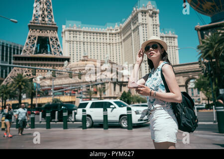 Freudige lady Tourist können Sie über online Karte app auf Handy und finden die richtige Richtung. Junge Mädchen gehen zu Sightseeing in Las Vegas. Backpacker lifest Stockfoto