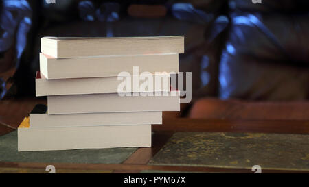 Stapel von Taschenbüchern auf einer Bibliothek Tabelle in ein dunkles Zimmer Stockfoto