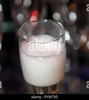 Glas Sekt mit einem sprudelnden cremigen Kopf und Soft Focus Hintergrund bokeh Stockfoto