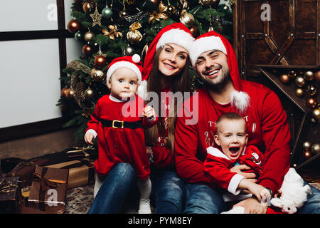 Glückliche Familie mit zwei entzückende Kinder, die Spaß am Weihnachtsbaum. Stockfoto