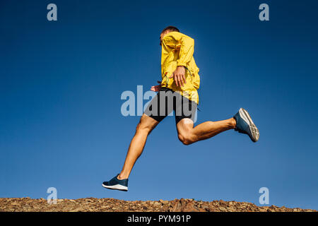Mann runner Sport Jacke in Gelb auf blauem Himmel Hintergrund Stockfoto