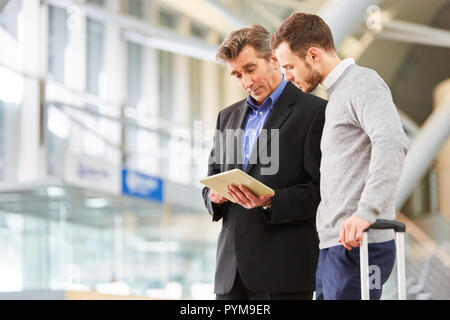 Zwei Geschäftsleute mit Tablet im Flughafenterminal diskutieren die Geschäftsreise Stockfoto
