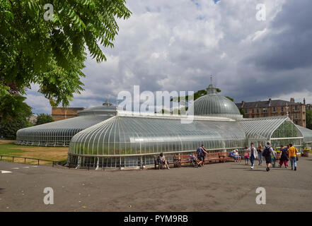 Der Kibble Palace Gewächshaus im Botanischen Garten in Glasgow, Schottland, Großbritannien, mit Leute sitzen auf Bänken im Freien. Stockfoto