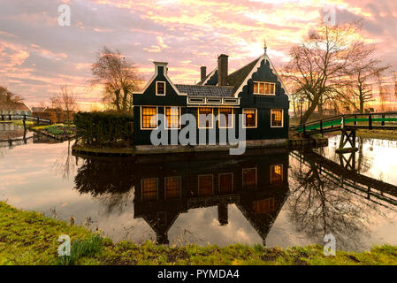 Schöne und typisch Holländischen Holzhäuser Architektur gespiegelt auf dem ruhigen Kanal von Zaanse Schans nördlich von Amsterdam, Niederlande Stockfoto