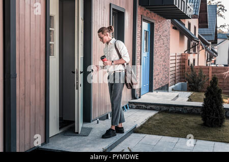 Stilvolle Geschäftsmann holding Tasten, während sein Haus betreten nach der Arbeit Stockfoto