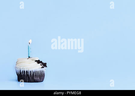 Ziemlich mit Schokoladegeschmack Cupcake mit vanilla buttercream frosting mit weißer Schokolade Späne, Schokolade, Chips und eine Kerze brennen eingerichtet. F Stockfoto