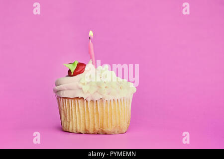 Ziemlich Erdbeere oder Kirsche aromatisiert frosted Cupcake mit weißer Schokolade Spänen und eine Kerze brennen eingerichtet. Freier Speicherplatz zum Kopieren von Text. Stockfoto