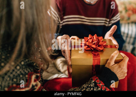 Nahaufnahme von einem älteren Paar hält ein Geschenkkarton. Senior Paar feiern Weihnachten den Austausch von Geschenken. Stockfoto