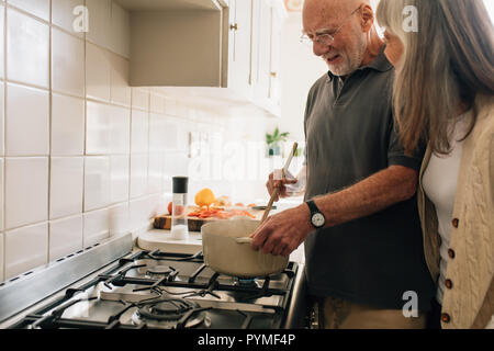 Ältere Menschen kochen, während seine Frau ist, mit ihm zu sprechen. Senior paar Ausgabe Zeit zusammen kochen. Stockfoto