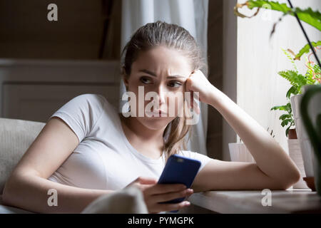 Traurig frustriert weiblichen Holding Smartphone sitzen auf der Couch Stockfoto