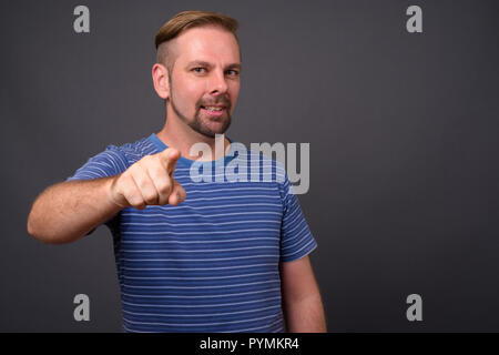 Blond bärtiger Mann mit Spitzbart gegen grauer Hintergrund Stockfoto