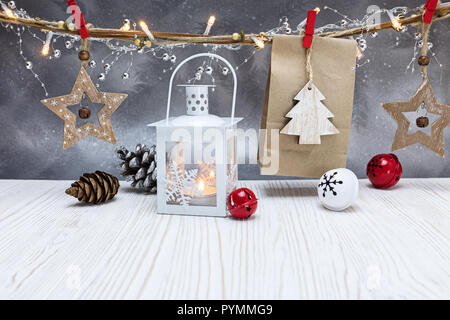 Winter Dekorationen auf weiße Holztisch. brennende Kerze Laterne, Papier-vorhanden-Taschen und Holzdekorationen gegen Festliche silberner Hintergrund Stockfoto