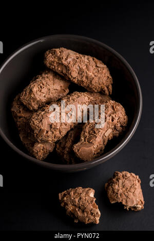 Die Pralinen in der Schüssel auf schwarzem Hintergrund. Stockfoto