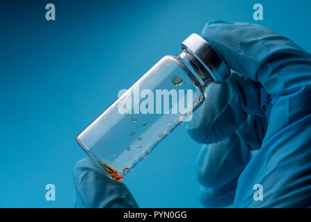 Eine behandschuhte Hand hält eine leere medizinische Flasche. Labor der medizinischen Forschung. Stockfoto