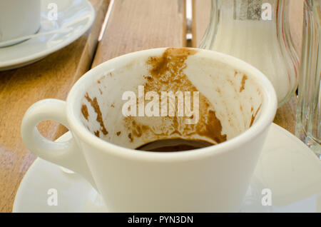 Weiße leere Tasse Kaffee mit Spuren von Kaffee auf Holztisch, Nahaufnahme, Outdoor im Restaurant Stockfoto