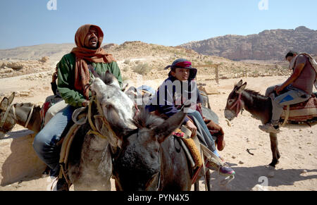 Bedouin Männer und Jungen neigen dazu, ihre Esel, Pferde und Kamele, Fahrten für Touristen in der Petra Archäologischen Park zu bieten, in Jordanien am 29. Oktober 2018 Stockfoto