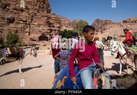 Bedouin Männer und Jungen neigen dazu, ihre Esel, Pferde und Kamele, Fahrten für Touristen in der Petra Archäologischen Park zu bieten, in Jordanien am 29. Oktober 2018 Stockfoto