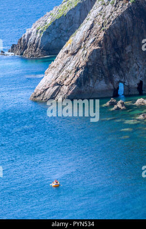 Playa del Silencio, Asturien, Spanien. Luftaufnahme von Kunststoff Schlauchboot in dunklen, blauen Meer Wasser mit Felsen im Hintergrund. Stockfoto