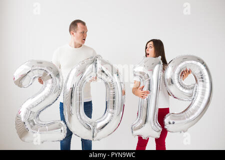 Neues 2019 Jahr kommt Konzept - Überrascht junger Mann und Frau sind Silber farbigen Zahlen im Innenbereich. Stockfoto
