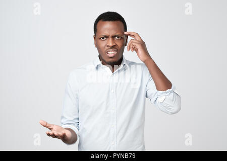 Junge europäische Mann im weißen T-Shirt unzufrieden runzelt die Stirn und blickt missmutig. Stockfoto