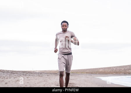 Einsame schwarze Rasse afrikanische ethnico diverse Runner am Strand. outdoor Sport anr Ausbildung für Afro Athlet läuft am Ufer mit Blick auf das Meer Ein Stockfoto