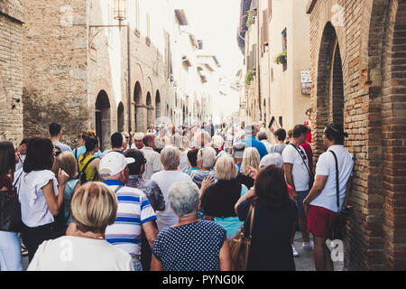 Masse der Touristen Menschen gehen zusammen gezogen und mit der Straße voll in San Gimignano in der Provinz Siena in der Toskana, Italien. Urlaub und Kultur in einem med. Stockfoto