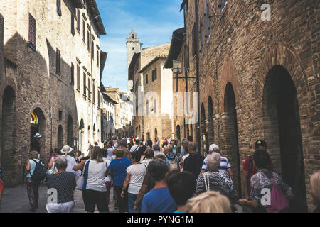 Masse der Touristen Menschen gehen zusammen gezogen und mit der Straße voll in San Gimignano in der Provinz Siena in der Toskana, Italien. Urlaub und Kultur in einem med. Stockfoto