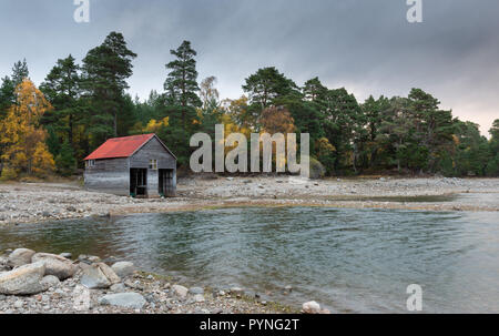 Ein red-roofed Bootshaus am Ufer des Loch Vaa in den schottischen Highlands, im Herbst mit den Bäumen ihre hellen Farben angezeigt. Stockfoto