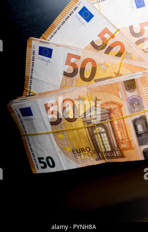 Stapel von 50 echten Euro-Banknoten 50-Euro-Banknoten unter Gummiband isoliert auf Schwarz backgrund über 20000 Euro wert. Stockfoto