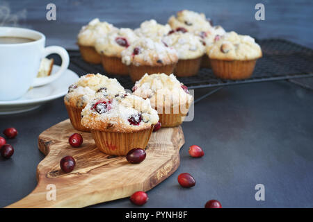 Cranberry Muffins auf einem Holz Schneidebrett mit mehr Kühlung auf Bäcker Zahnstange. Extrem flache Tiefenschärfe mit selektiven Fokus auf Muffin in foregro Stockfoto