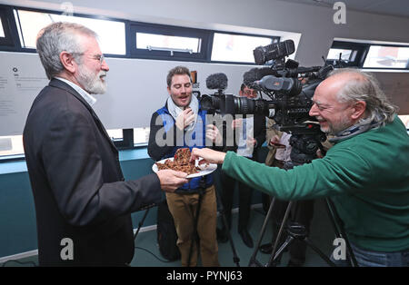 Der ehemalige Sinn-Fein-Anführer Gerry Adams übergibt den Medien Weihnachtspudding bei der Veröffentlichung seines Rezepturbuches mit dem Titel The Negotiators' Cookbook im Culturlann on the Falls Road in Belfast. Stockfoto