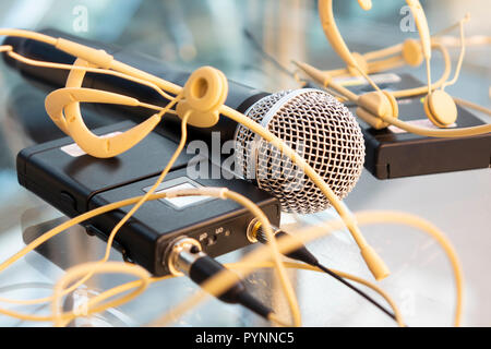 Zwei Head Set drahtlose Mikrofone Sender und hand Mikrofon; drahtloses Mikrofon Empfänger auf Glas Tisch im TV-Studio Stockfoto