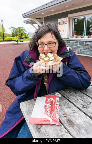 Frau essen eine Schokolade & Banane BeaverTail außerhalb einer BeaverTails Gebäck stand in Bannerman Park in St. John's, Neufundland, Kanada. Stockfoto