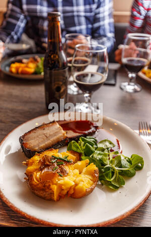 Gegrillte Schweinerippchen mit BBQ Sauce, gebackene Kartoffeln und frischen Babyspinat Stockfoto